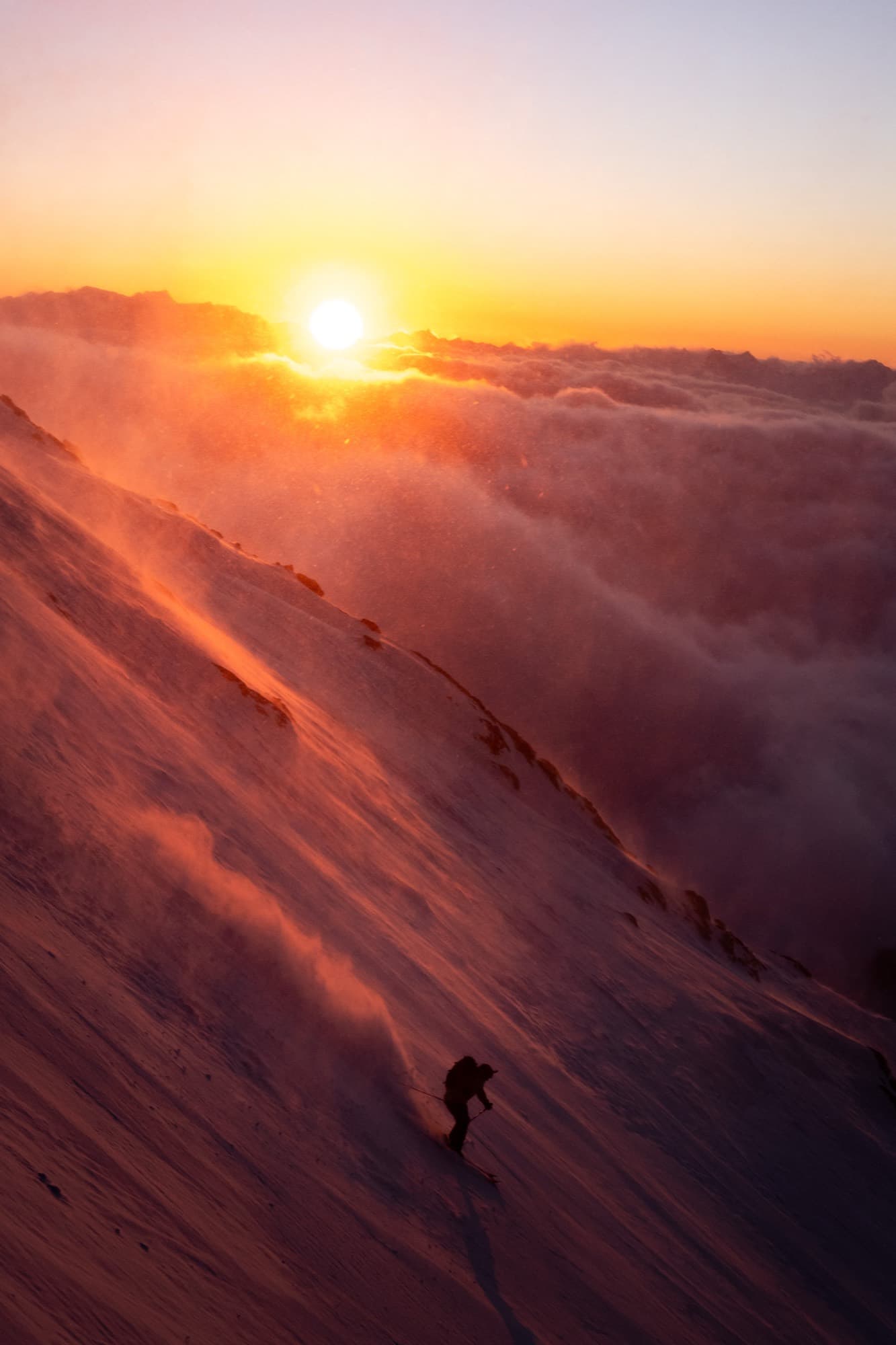 Skieur en silhouette au-dessus d'une mer de nuages au coucher du soleil, hors-piste dans les Trois Vallées