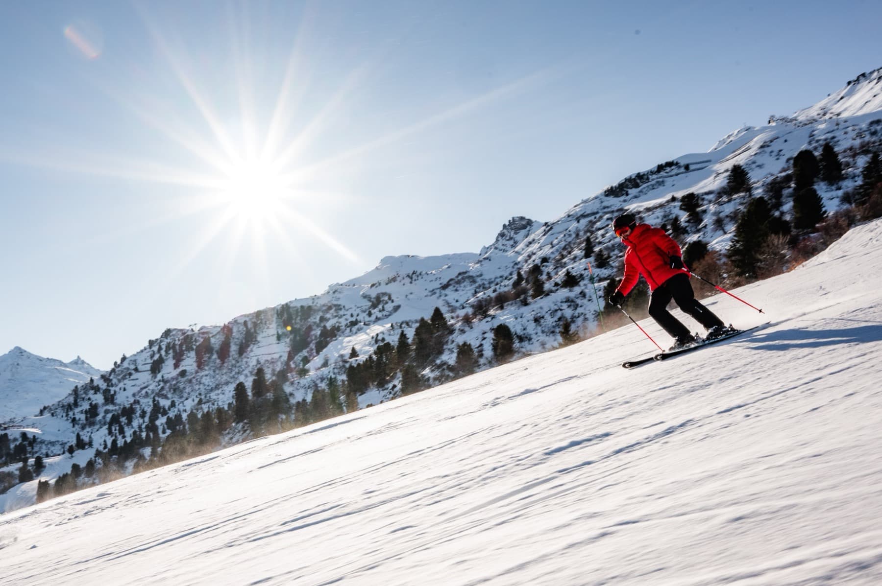 Cours de ski sur piste à Courchevel, Trois Vallées — moniteur en veste rouge sous un ciel bleu